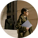 A woman wearing a coat and glasses is holding a folder